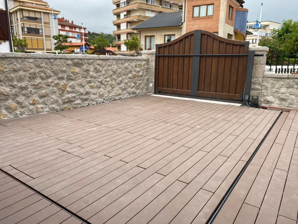 Acabado final de instalación de tarima exterior en Madrid con canaleta de desagüe y muro de piedra